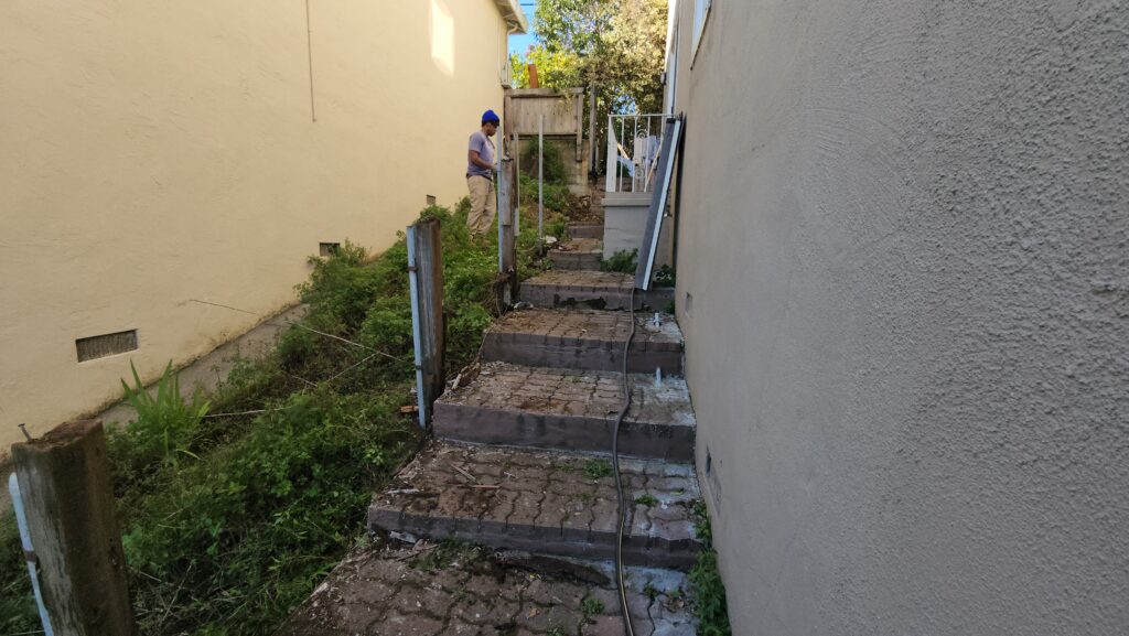 All Access Construction removing old damaged brick stairs during the Belmont hillside staircase demolition.