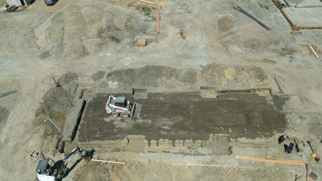 Aerial drone shot of All Access Construction grading the Milpitas carport slab area, showing excavation layout and surrounding Silicon Valley landscape.