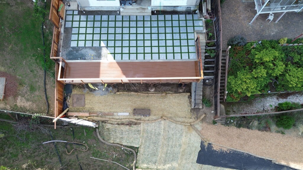 All Access Construction drone top view showing new deck, retaining wall, erosion control fabric, and slope stabilization in Belmont.