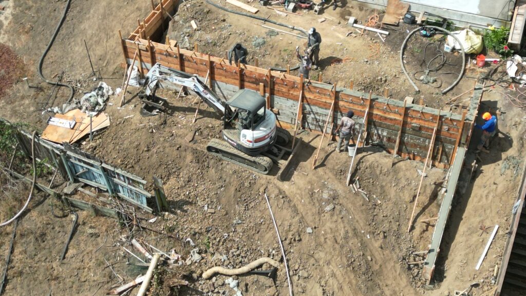 All Access Construction crew forming and bracing concrete retaining wall along steep slope in Belmont, San Mateo County.