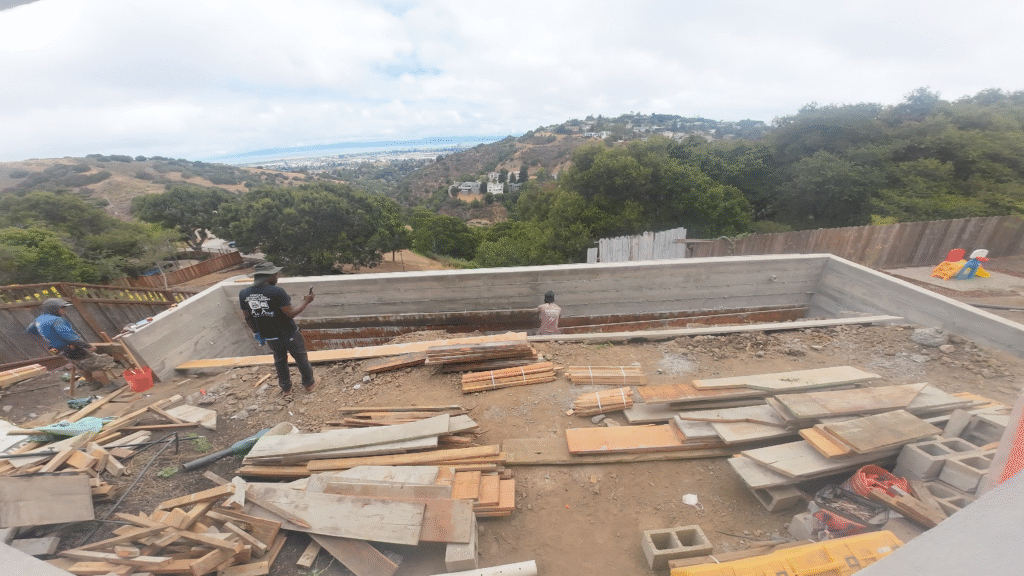 All Access Construction drone view of completed concrete retaining wall in Belmont with crew stripping forms and cleaning the workspace.