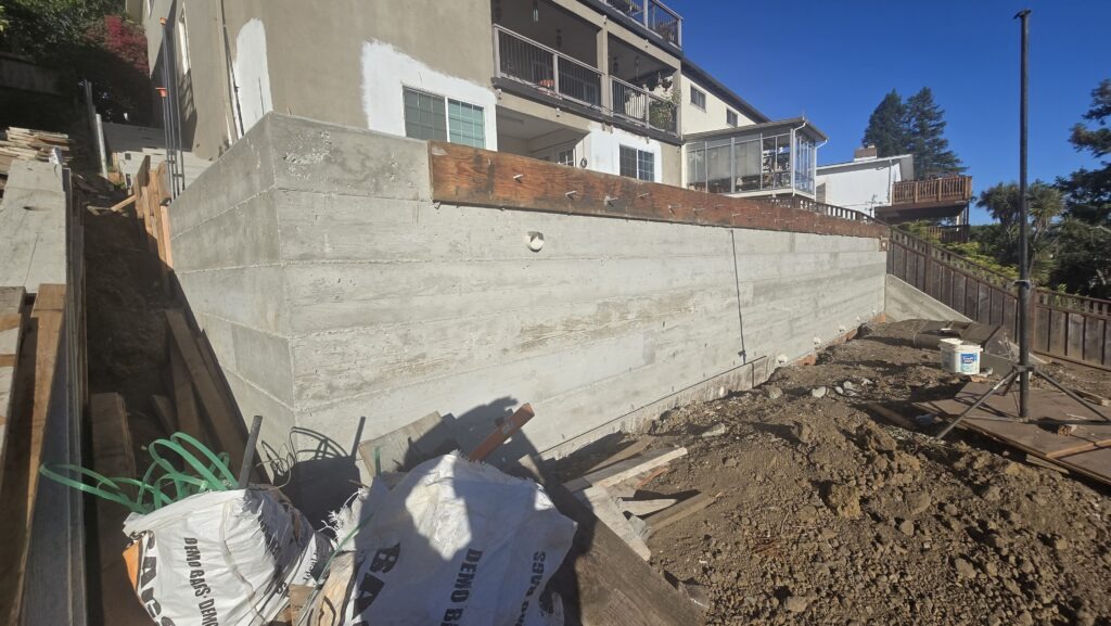 All Access Construction side view of newly poured concrete retaining wall in Belmont, showing board-form texture and clean structural finish.