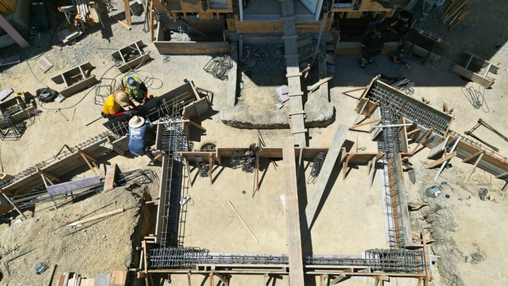 rone view of Milpitas hillside construction site showing concrete foundation work, access driveway, and South Bay terrain.