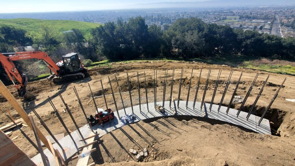 Curved concrete retaining wall excavation and vertical rebar installation in Milpitas CA near San Jose Santa Clara County before concrete pour