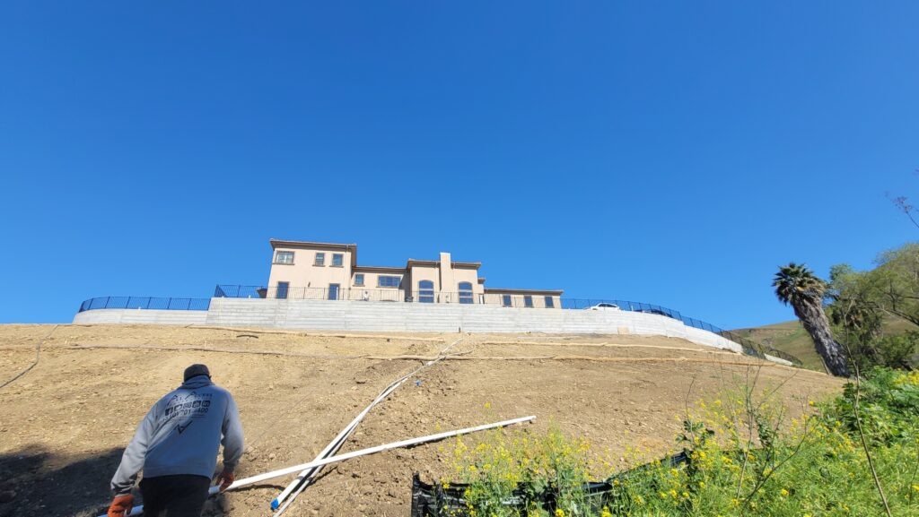 Wide hillside view of completed curved concrete retaining wall near San Jose Milpitas California