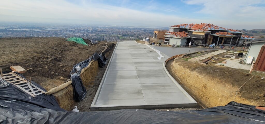All Access Construction finishing new Milpitas hillside driveway concrete pour on fire access road