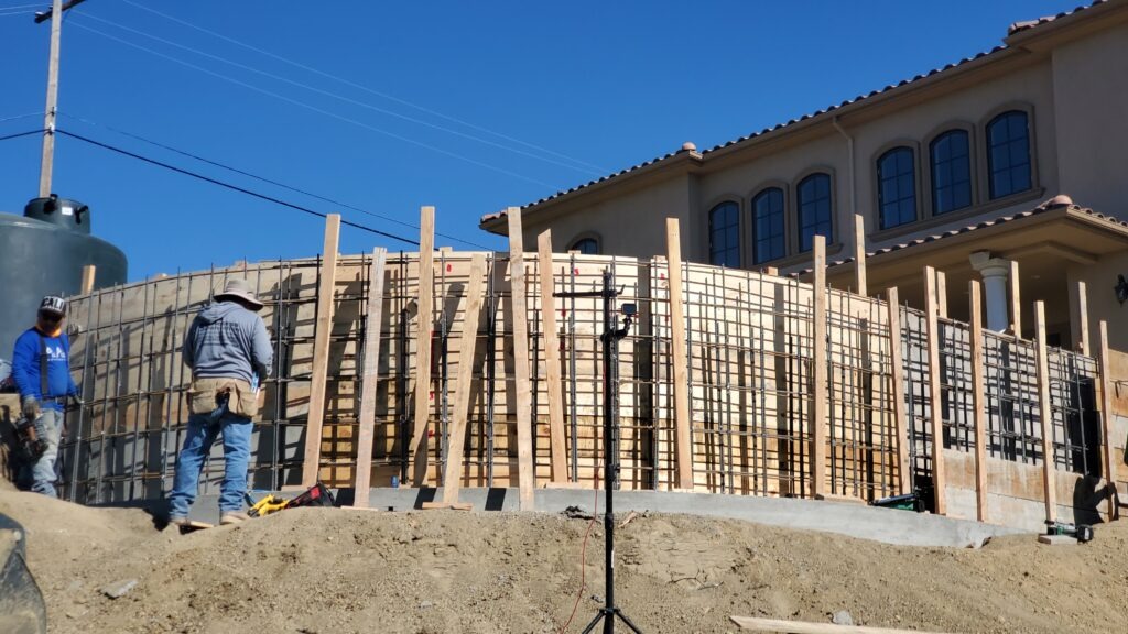 Close-up of curved retaining wall rebar and forming during hillside construction in Milpitas CA near San Jose