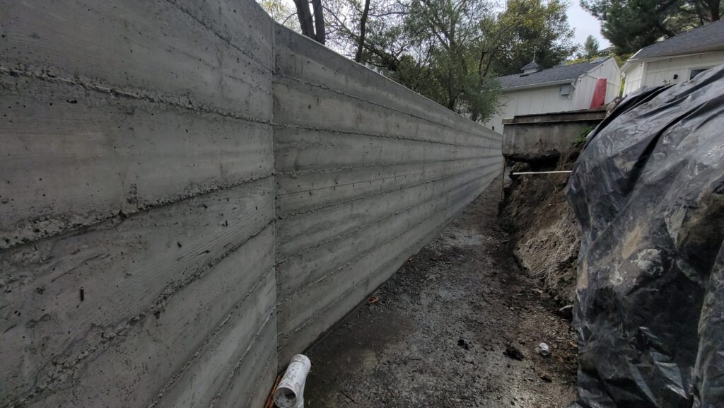 Long hillside concrete retaining wall in Walnut Creek after form removal, showing clean lines and drainage area
