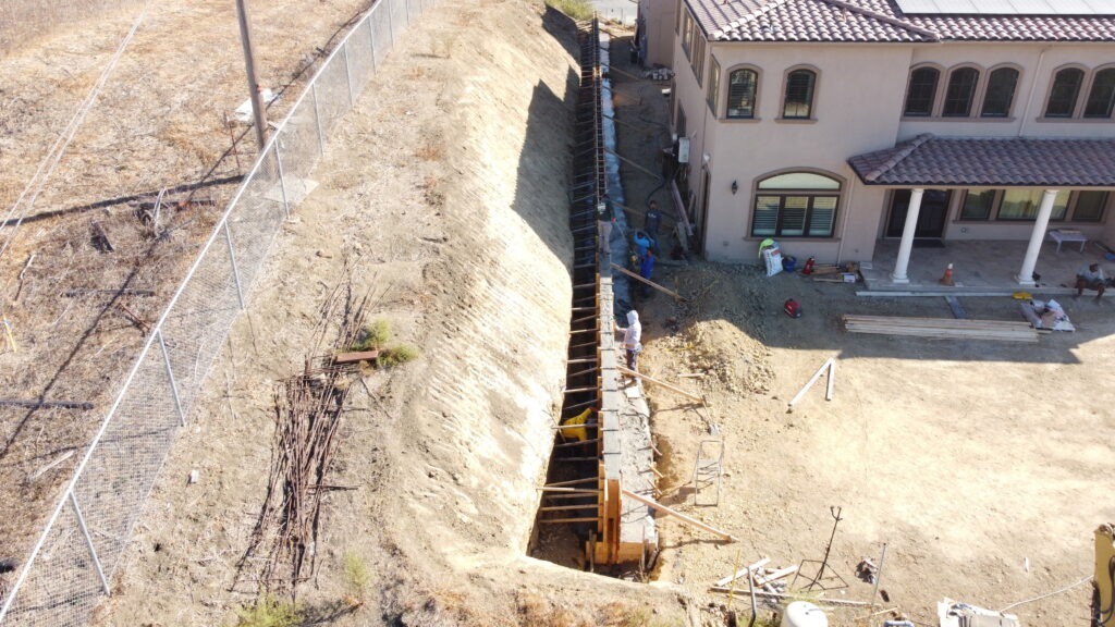 Aerial view of concrete retaining wall construction behind a home in Milpitas CA Santa Clara County