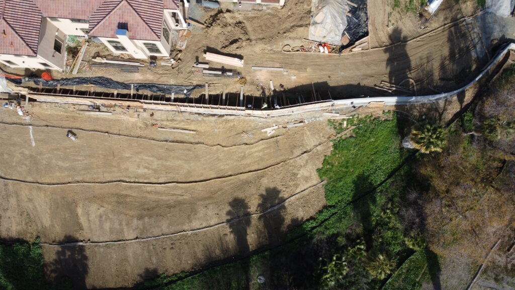 Hillside drainage and erosion control installed in front of long concrete retaining wall in Milpitas